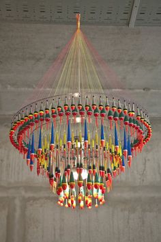 a colorful chandelier hanging from the ceiling in a room with concrete walls and flooring