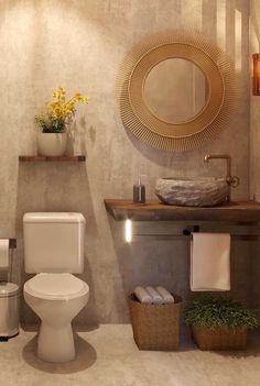 a white toilet sitting next to a sink in a bathroom under a round gold mirror