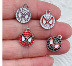 four spiderman charms in different colors and shapes