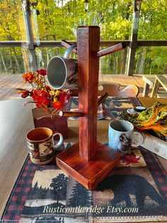 a wooden table topped with cups and mugs on top of a carpeted floor