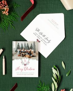 an envelope with a christmas card on it next to other holiday decorations and greenery