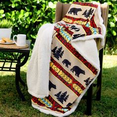 a blanket sitting on top of a chair next to a table with a coffee cup