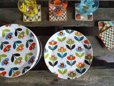 two plates with flower designs on them are sitting next to each other near glass dishes