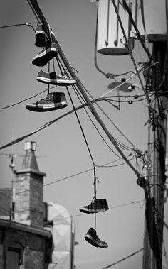 several pairs of shoes hanging from power lines