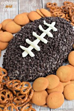 a football shaped cake surrounded by cookies and pretzels