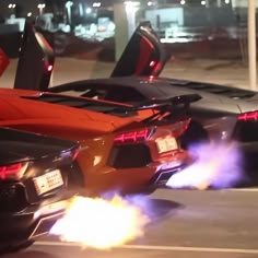 two sports cars with their doors open on the street in front of a parking lot at night