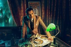 a man in a suit and tie looking at a magazine on a table with a lamp