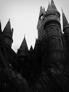 black and white photograph of hogwart's castle from the ground up on a hill