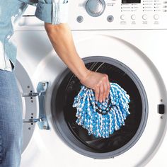 a person is cleaning the front of a washing machine with blue and white rags