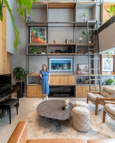 a woman standing in front of a living room filled with furniture and bookshelves