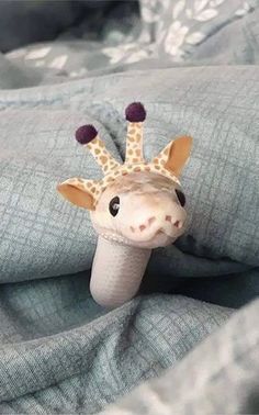 a stuffed giraffe sticking its head out of a tube on top of a blanket