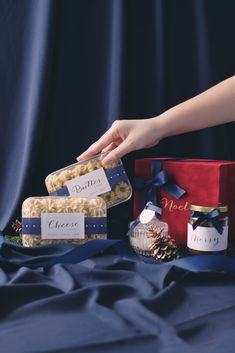 a person reaching for some kind of cracker in front of two boxes with pine cones on them