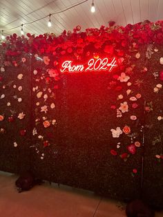 a red neon sign that reads prom 2074 with flowers on the wall behind it