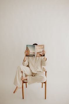 a man sitting in a chair while reading a book with his legs crossed and feet crossed