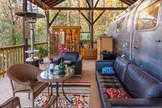 a living area with couches, chairs and a table on the deck in front of an rv