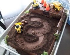 a birthday cake with construction trucks on top and dirt in the shape of an o