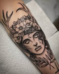 a woman's face with flowers on her head is shown in this tattoo design