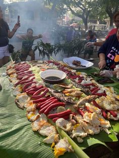 people standing around a table with food on it and hot dogs in front of them