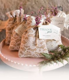 three small bags filled with purple flowers on top of a pink plate