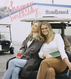 two women are sitting on a golf cart