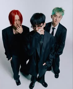 three young men in black suits and green hair posing for a photo with their hands on their chins