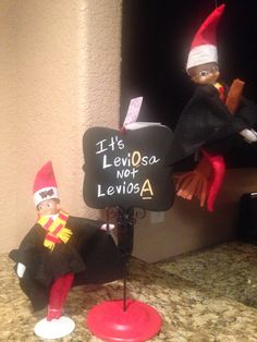 two elfs sitting on top of a counter next to a sign that says it's leviosa not leviosa