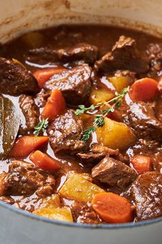 beef stew with carrots, potatoes and parsley in a pot on the table