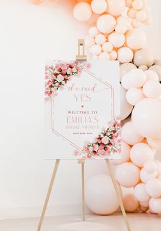 a welcome sign with pink flowers and white balloons in front of a backdrop that says, the god yes