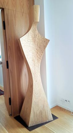 a wooden sculpture sitting on top of a hard wood floor next to a door in a room