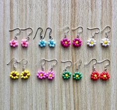 small flower earrings are displayed on a wooden surface, with the word love spelled in white letters