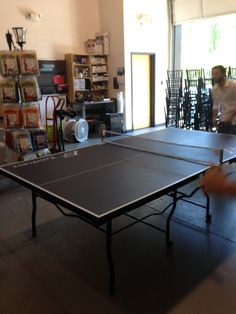 two people playing ping pong in an open room