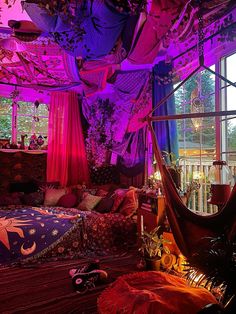 a bedroom with purple lights and lots of pillows on the bed, in front of a large window