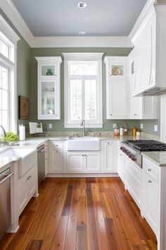 a kitchen with white cabinets and wood floors