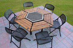 an outdoor table and chairs set up on a brick patio with grass in the background