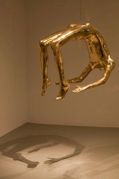 a gold sculpture hanging from the ceiling in a room with white walls and flooring