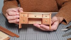 a person is holding a miniature desk made out of wood and some other tools on the table