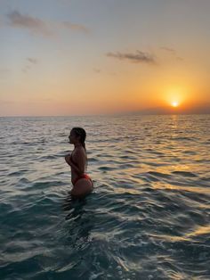 a woman in the ocean at sunset