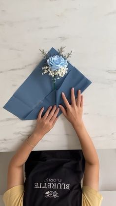 a woman holding up a blue envelope with flowers on it and the word bridalle in front of her