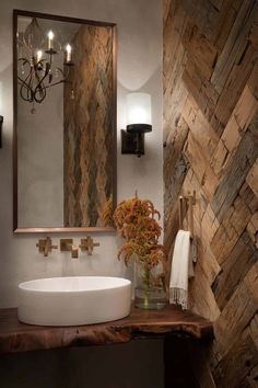 a bathroom sink sitting under a mirror next to a wooden counter top with a vase filled with flowers