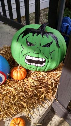 two pumpkins with faces painted on them sitting in hay next to other pumpkins