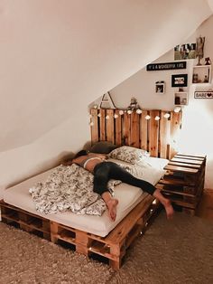 a woman laying on top of a bed made out of pallet wood planks