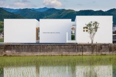 two white buildings sitting next to each other near a body of water with mountains in the background