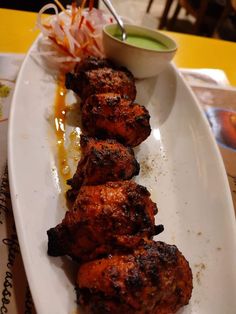 some chicken is on a white plate with sauce and garnish in the background