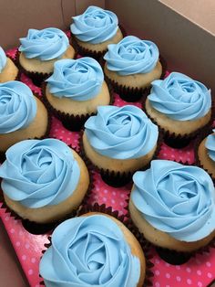 a box filled with blue frosted cupcakes sitting on top of a table