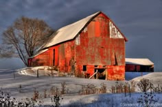 an old red barn sits in the snow