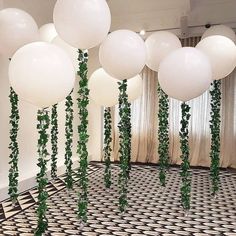 white balloons and greenery are hanging from the ceiling in an art deco style room