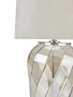 a glass lamp with a white shade on it's base and a light bulb in the middle