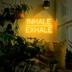 a neon sign that reads inhale exhale on the side of a wall above a couch