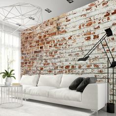 a white couch sitting in front of a brick wall next to a table and chair