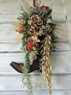 a cowboy boot with flowers and feathers hanging on the wall next to a white door